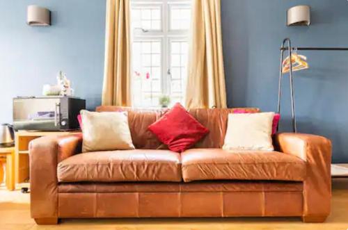 a brown leather couch with pillows in a living room at Kingswood in Bromley