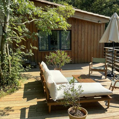 - une terrasse avec 2 chaises longues et un parasol dans l'établissement Le Petit Chai Fronsadais, à Saint-Michel-de-Fronsac