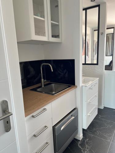 une cuisine avec des armoires blanches et un évier dans l'établissement Au 69 du Village Naturiste, au Cap d'Agde