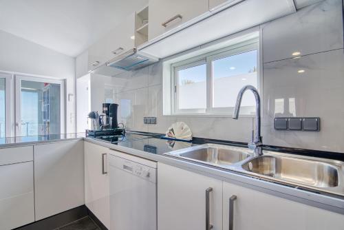 a white kitchen with a sink and a window at Casa al Mar in Maspalomas