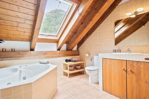 Un baño con bañera, inodoro y ventana. en Apartament Dúplex amb encant a l'alta muntanya - Saraís, en Durro