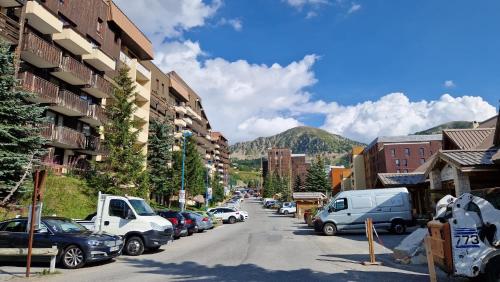 a busy street in a town with cars parked at Studio central proche des pistes in Isola