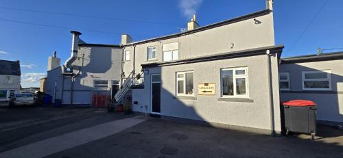 a white building with a window and a garage at Links Lets Room Only in Seahouses