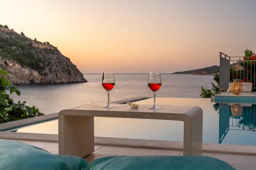 two glasses of wine sitting on a table next to the ocean at AssosView in Asos