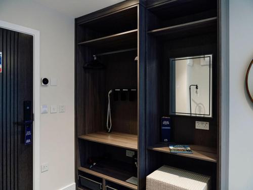 a wooden cabinet with a mirror in a room at Hotel De Normandie in Saint Helier Jersey
