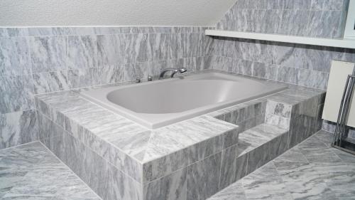 a white bath tub in a bathroom with gray tiles at Art Haus Penthouse Winterberg in Winterberg