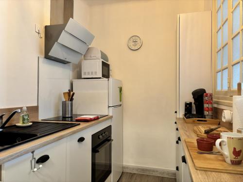La cuisine est équipée d'un réfrigérateur blanc et d'un four micro-ondes. dans l'établissement Le 130 - 1 chambre - Wifi - Proche Parc Thermal - 2 personnes, à Châtel-Guyon