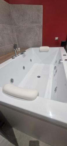 a white bath tub in a bathroom with a red wall at Hotel Movida in Casoria