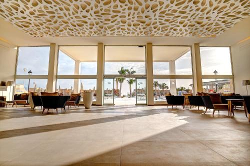 a lobby with tables and chairs and large windows at SBH Monica Beach Resort in Costa Calma