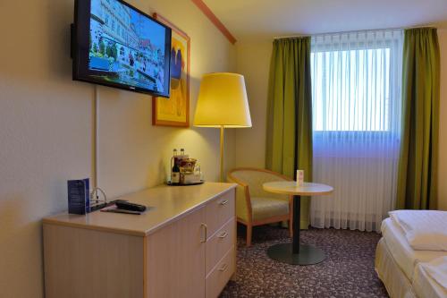a hotel room with a bed and a tv on the wall at PLAZA INN Leonberg in Leonberg