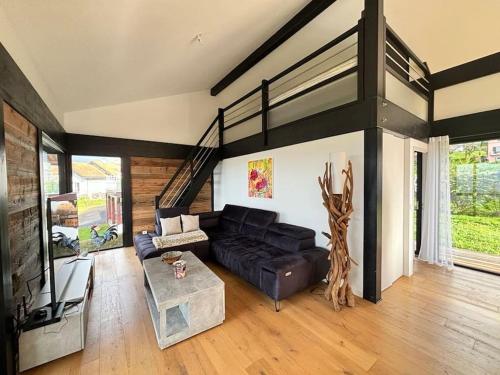 un salon avec un canapé noir et une table dans l'établissement Magnifique Villa Vue Lac, à Évian-les-Bains