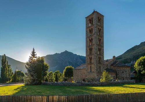un antiguo edificio de piedra con una torre en un campo en Apartament Dúplex amb encant a l'alta muntanya - Saraís, en Durro