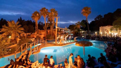 un groupe de personnes assises autour d'une piscine la nuit dans l'établissement Camping 4 étoiles - Parc aquatique - efacfc, à Hyères