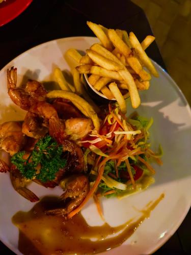 a plate of food with shrimp and french fries at Golden Town Hotel in Tangalle