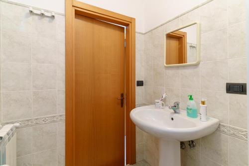 a bathroom with a sink and a wooden door at Little Rose garden in Aci Catena
