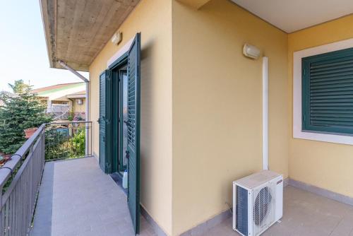 a door to a house with a fan on a balcony at Little Rose garden in Aci Catena