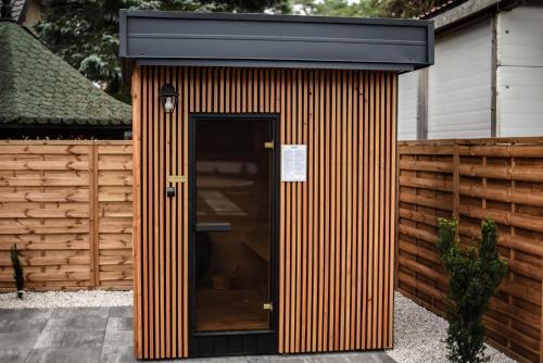 a wooden shed with a door and a fence at Dream Holiday z Sauna i jacuzzi Lovely Krynica Zdrój in Florynka