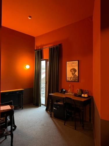 an orange room with a table and a window at Hotel Memoire Kutaisi in Kutaisi