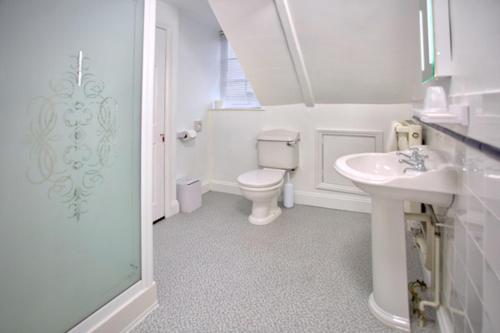 a white bathroom with a toilet and a sink at The Palmerston Rooms in Romsey