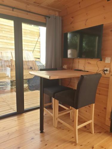 une table et une chaise dans une chambre avec une télévision dans l'établissement Studio cabane, à La Bucaille