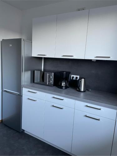 a kitchen with white cabinets and a refrigerator at Haus KaiserInn - komfortable Wohnung 82 qm TOP ausgestattet, 2 Schlafzimmer mit Balkon und Bergblick in Flintsbach