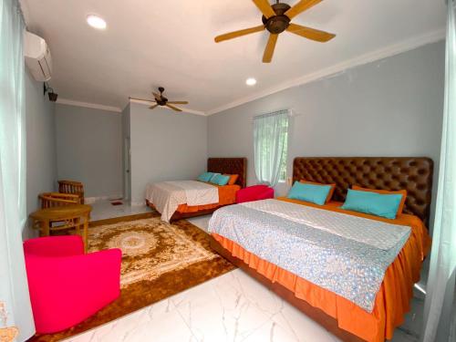 a bedroom with two beds and a ceiling fan at Pelamin Garden Homestay & Wedding in Lengging