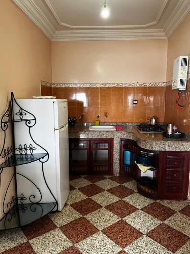 a kitchen with a white refrigerator and a checkered floor at Vu sur corniche in Safi