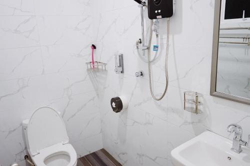 a white bathroom with a toilet and a sink at Pelamin Garden Homestay & Wedding in Lengging