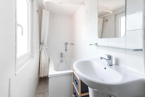 La salle de bains blanche est pourvue d'un lavabo et d'une baignoire. dans l'établissement CAPUCIN, à Rouen