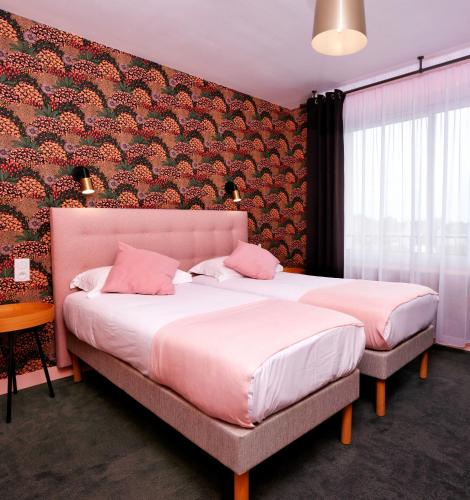 a bedroom with two beds with pink pillows at The Originals City, Hôtel Armen Le Triton, Roscoff in Roscoff