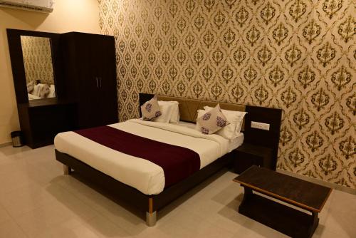 a bedroom with a bed and a wall with wallpaper at Vijayam Resort in Nāthdwāra