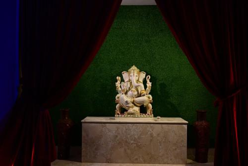 a statue on a table with a green wall at Vijayam Resort in Nāthdwāra