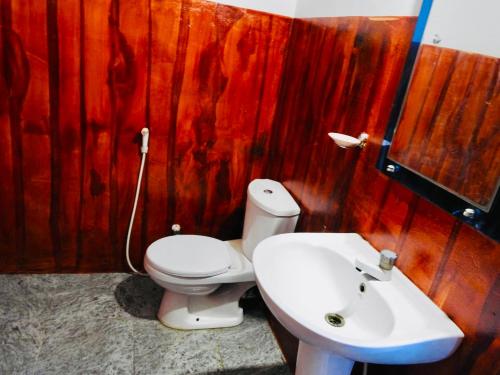 a bathroom with a white toilet and a sink at Cozy Sand Beach Hotel in Arugam Bay