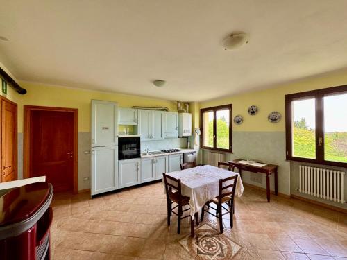 a kitchen with white cabinets and a table with chairs at R&B Del Monte in Forlì
