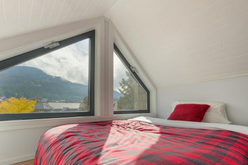 Un dormitorio con una cama y una ventana grande. en Tantalus Penthouse Mountain and Village Views, en Whistler