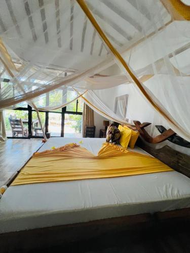 a large bed with yellow pillows on top of it at Z-Love Zanzibar in Kiwengwa
