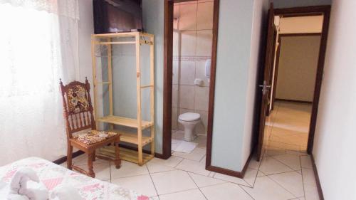 a bathroom with a toilet and a chair and a mirror at Pousada bonomo in Urubici