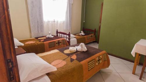 a room with three beds with towels on them at Pousada bonomo in Urubici