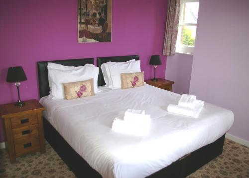 a bedroom with a large white bed with purple walls at The Black Dog Inn in Broadmayne