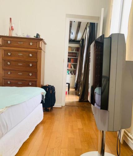 - une chambre avec une télévision, un lit et une commode dans l'établissement Lux Apartment Marais Temple, à Paris