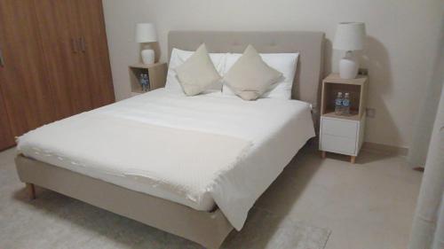 a bedroom with a bed with white sheets and pillows at P one Hotel apartment in Jebel Dhanna