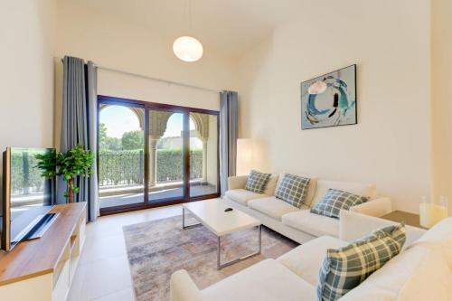 a living room with white furniture and a large window at Serene 2-Bed Haven in Jumeirah Golf Estates in Dubai