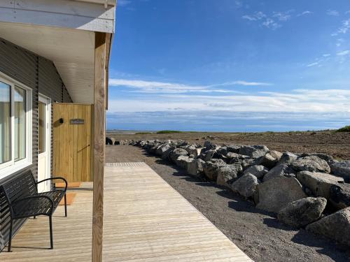a porch of a house with a bench and rocks at Strönd Guesthouse in Birkimelur 