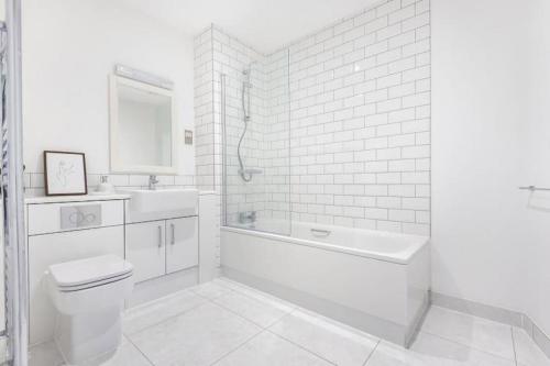 a white bathroom with a tub and a toilet and a sink at Luxury 5* Marina Apartment in Langstone