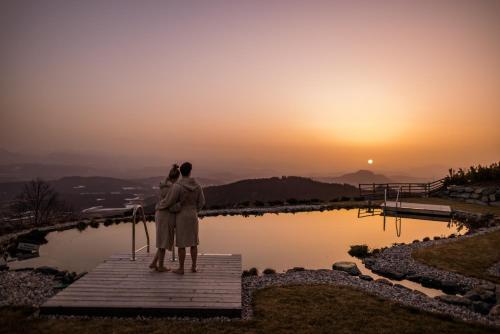 a couple standing on a dock looking at the sunset at Gipfelhaus Magdalensberg in Sankt Veit an der Glan