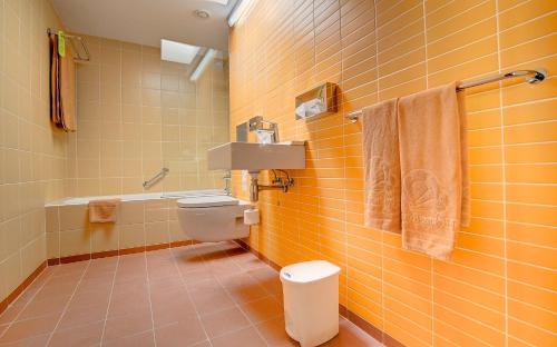 Baño de azulejos amarillos con aseo y lavamanos en SBH Monica Beach Resort, en Costa Calma