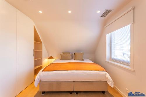 Un dormitorio con una cama con una manta naranja. en Marie, en Koksijde