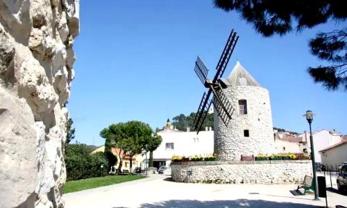 a windmill in front of a white building at Petit Cocon cosy au cœur du village d'Allauch in Allauch