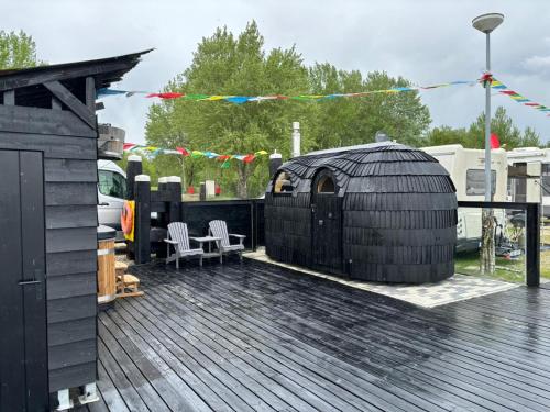 a black gazebo on top of a deck at Houseboot Kingfisher, lake view in Biddinghuizen