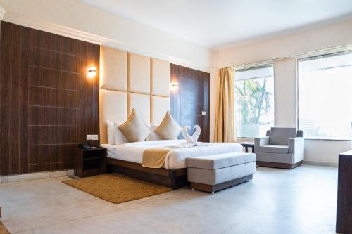a bedroom with a large bed and a chair and window at Pride Premier Solitaire in Dehradun